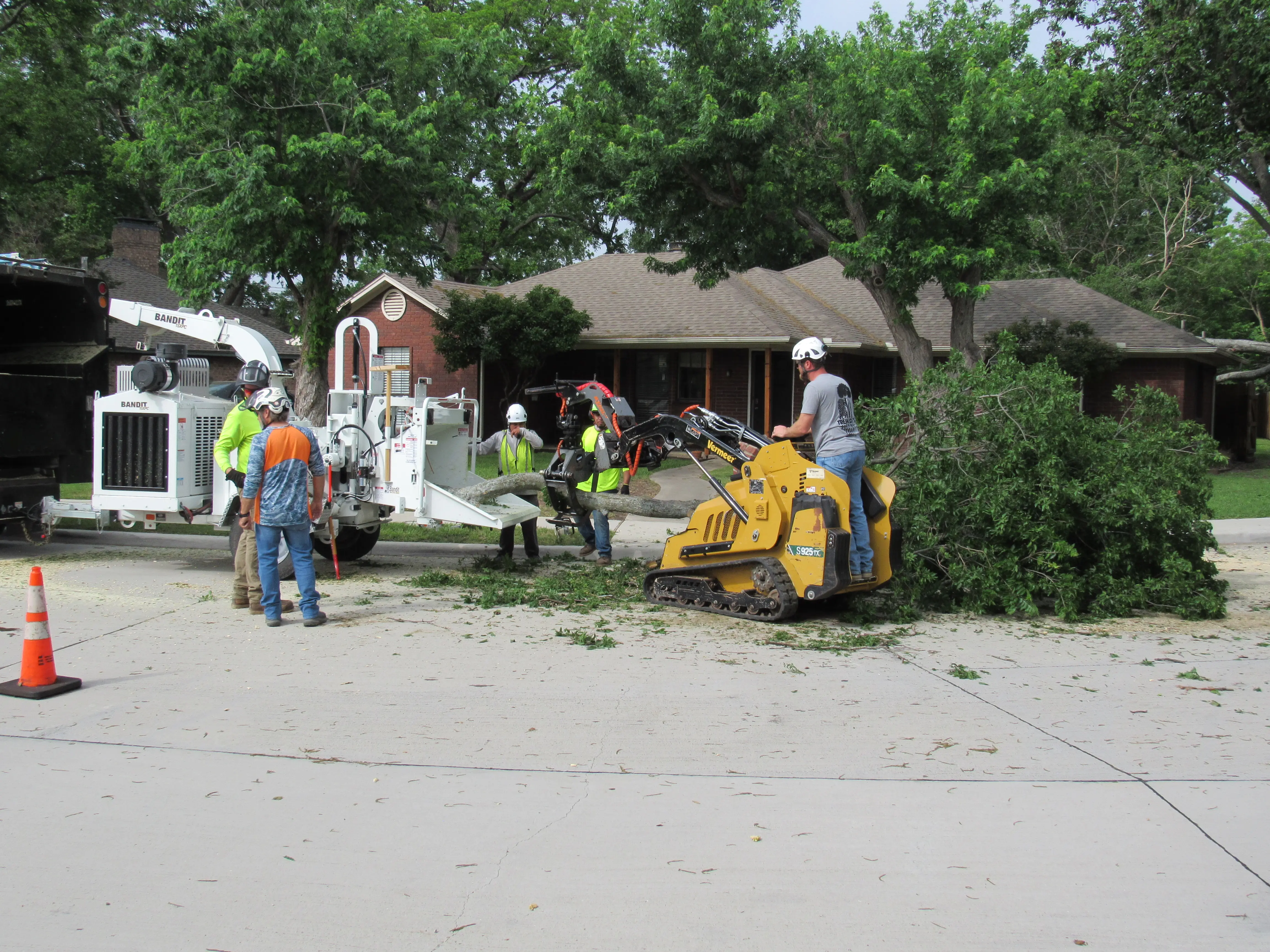 Tree MD's crew using a Vermeer mini skid steer to feed branches into a Bandit chipper during emergency cleanup in McKinney, TX